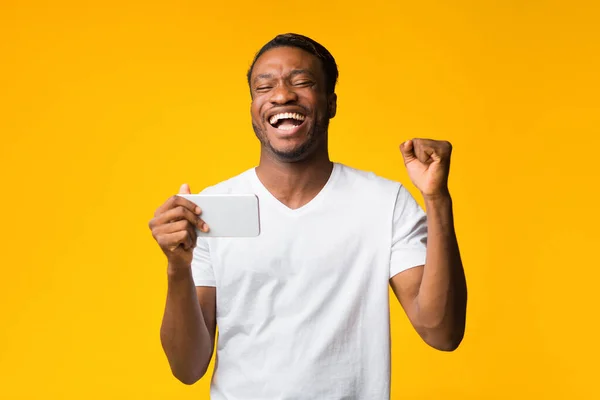 Afroamericano uomo holding cellulare agitazione pugni standing in studio — Foto Stock