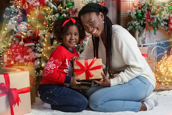 Sorrindo afro-americana mãe e filha posando com presente de Natal — Fotografia de Stock