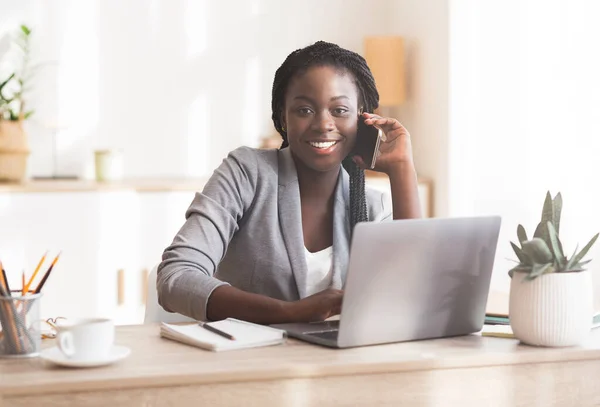 Sonriente mujer africana gerente hablando en el cliente de consultoría de teléfonos celulares —  Fotos de Stock