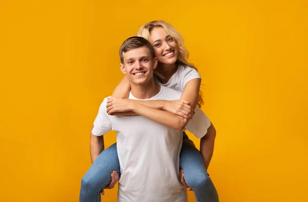 Sorrindo jovem cara carregando namorada em suas costas — Fotografia de Stock