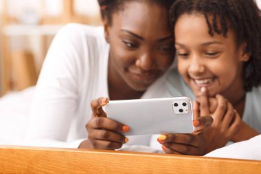 Afro anne ve çocuk iPhone 11 'de maksimum düzeyde video izliyorlar.