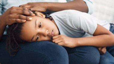 Close-up of black girls head laying on lap clipart