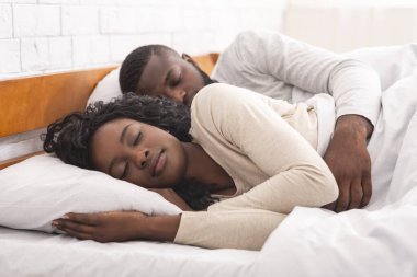 Afro çift evde rahat bir yatakta yatıyor.