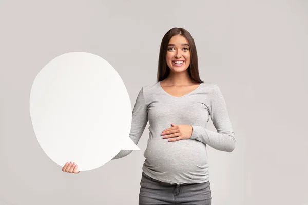 Mujer embarazada sosteniendo la burbuja del discurso de pie sobre fondo gris, burla —  Fotos de Stock