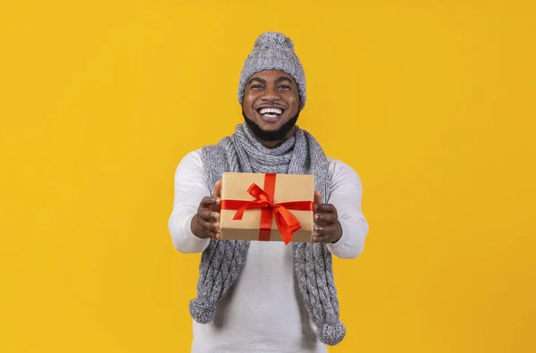 Wesoły młody czarny mężczyzna daje prezent świąteczny — Zdjęcie stockowe