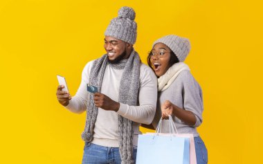 Neşeli siyah adam ve kız akıllı telefondan online alışveriş yapıyorlar.