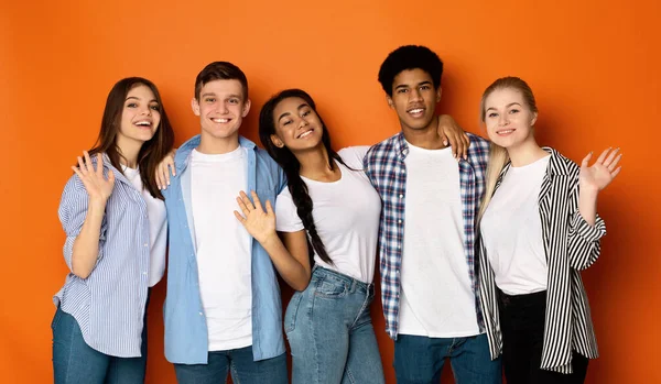 Teen friends saying hello and waving hands to camera