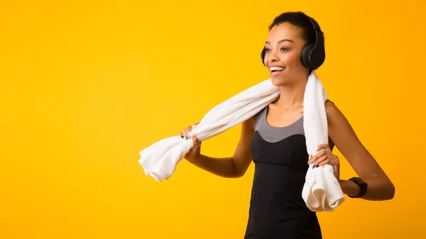 Afro-Frau mit Kopfhörer hört Musik im Stehen, gelber Hintergrund, Panorama — Stockfoto