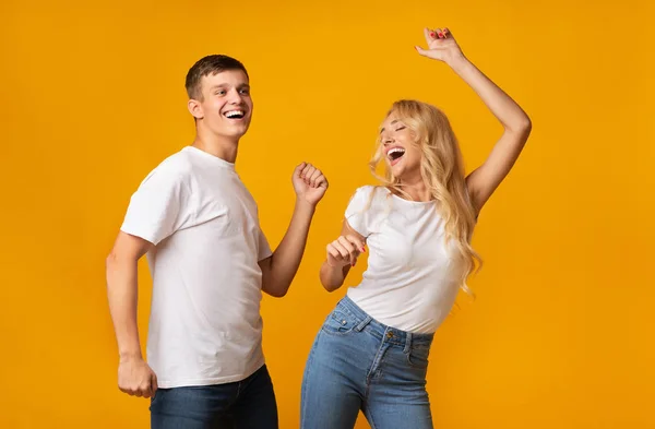 Joyeux millénial gars et fille dansant sur fond jaune studio — Photo
