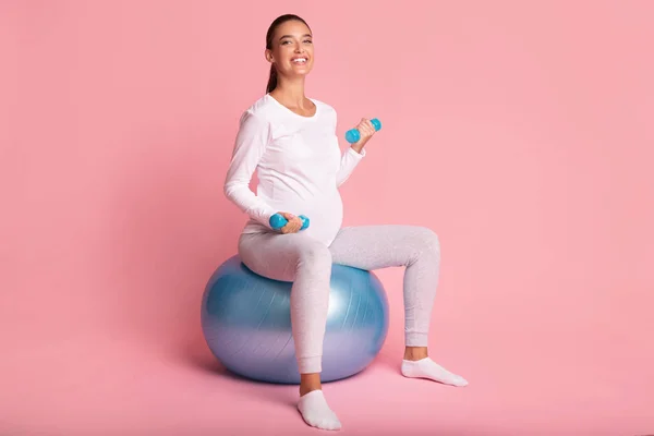 Verwachte dame oefenen met dumbbells zitten op Fitball, Studio schot — Stockfoto