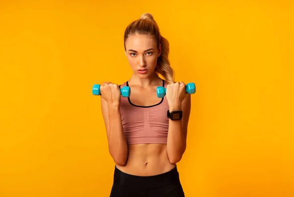 Mujer decidida haciendo ejercicio con sombrillas de pie sobre fondo amarillo — Foto de Stock