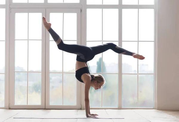 Junge sportliche Frau balanciert auf Händen mit gespaltenen Beinen — Stockfoto