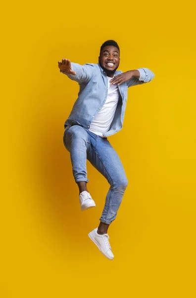Engraçado afro cara pulando e fazendo movimentos de karatê no fundo amarelo — Fotografia de Stock