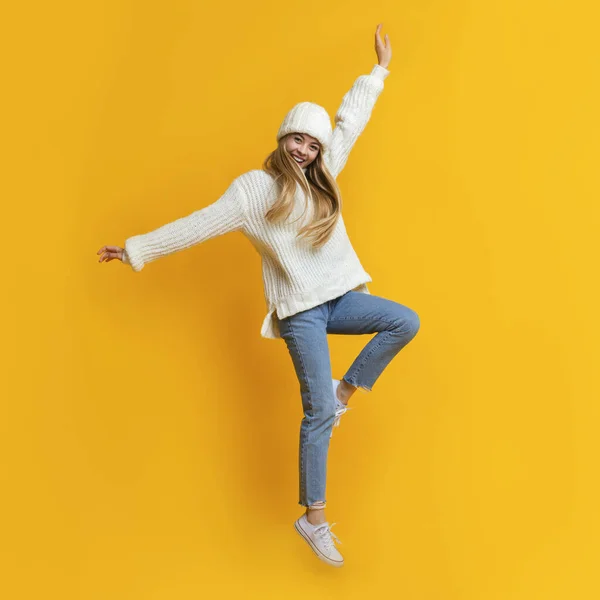 Грайлива зимова дівчина розважається на жовтому студійному фоні — стокове фото