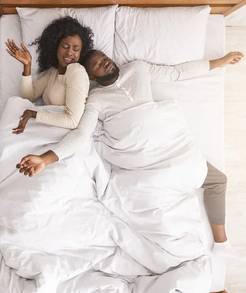 Африканська дружина роздратована чоловіком, який розтягнувся по всьому ліжку. — стокове фото