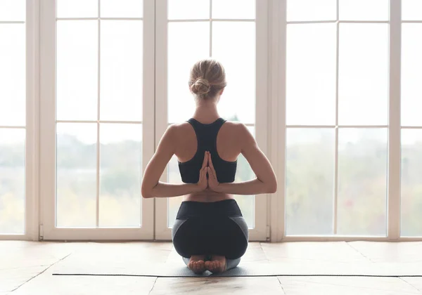 Back view of girl meditating in reverse prayer pose