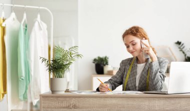 Genç moda tasarımcısı müşterilerin siparişlerini telefonda tartışıyor