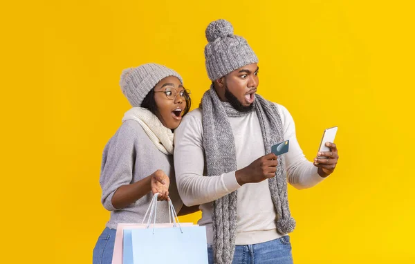 Sorprendida pareja afro mirando el teléfono inteligente, compras en línea — Foto de Stock