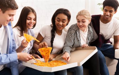 Mutlu arkadaşlar buluşmayı kutluyor, sıcak pizza yiyor.