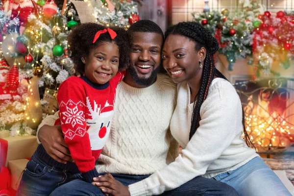 Joyful african american family of three posing in Christmas interior