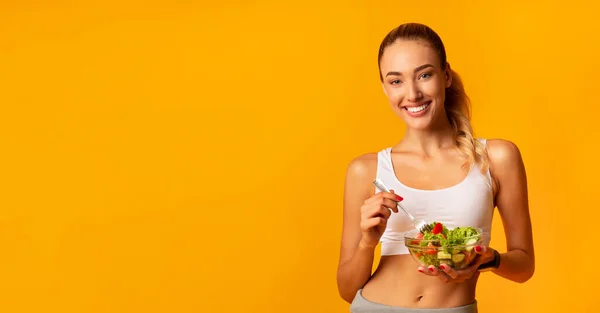 Fit Mädchen essen Gemüsesalat im Stehen vor gelbem Hintergrund, Panorama — Stockfoto