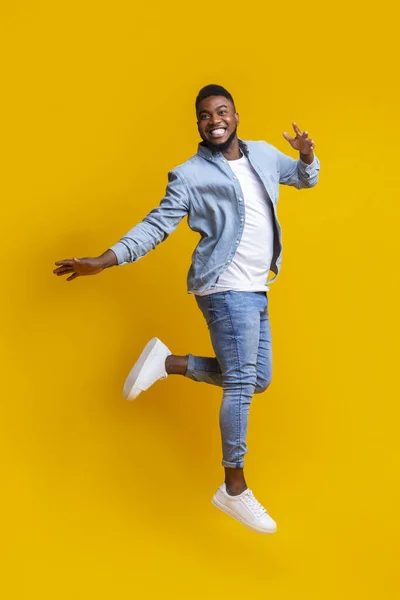 Portrait of funny black man jumping on yellow background — Stock Photo, Image