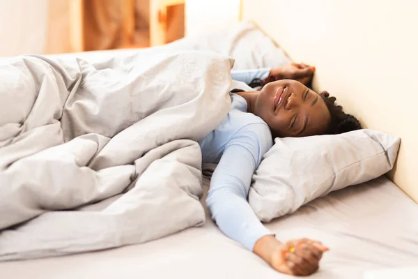 Afro-Mädchen streckt Hände, die zu Hause im Bett aufwachen — Stockfoto