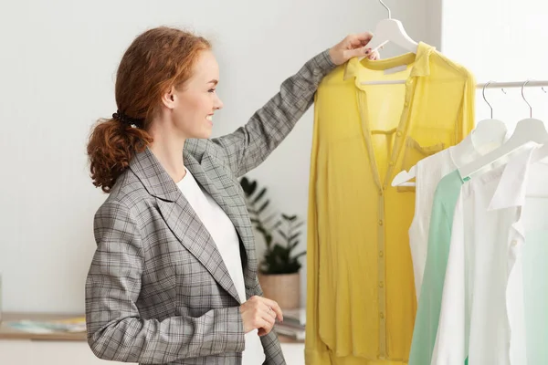 Successful fashion designer looking at ready for sale shirt — Stock Photo, Image