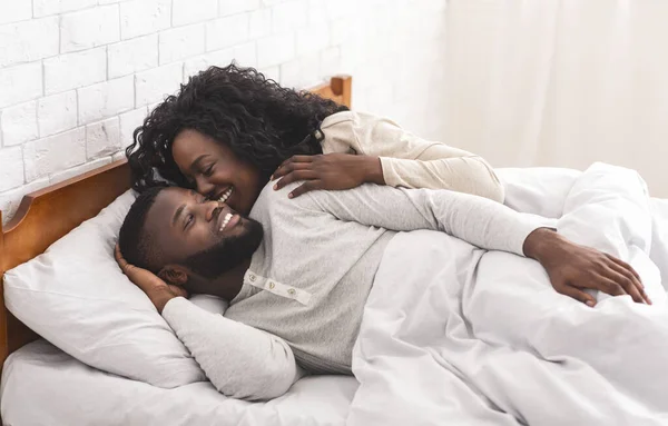 Liebendes schwarzes Paar hat Spaß im Bett, küsst und umarmt — Stockfoto