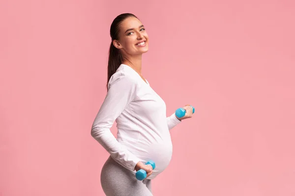 Positif Expectant Woman Exercising Dengan Dumbbells Berdiri di Studio — Stok Foto