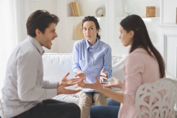 Psicólogo confuso assistindo jovem casal discutindo em seu escritório — Fotografia de Stock