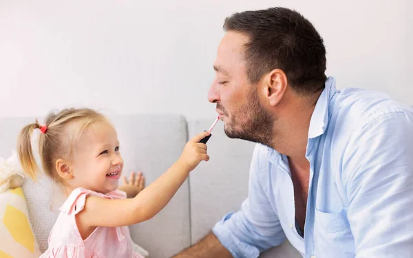 Little daughter doing makeup to her daddy — ストック写真
