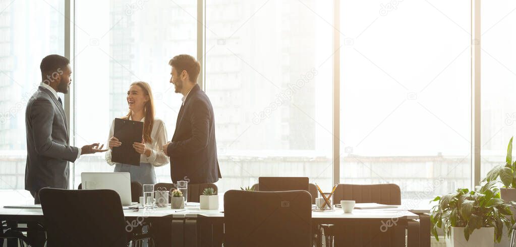 Successful businesspeople talking together in front of office windows