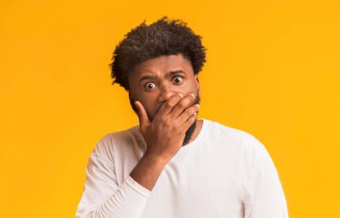 Şaşkın siyah adam ağzını avuç içiyle kapatıyor.