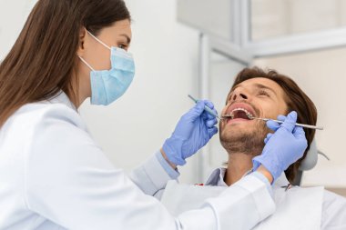 Diş sağlığı kliniğinde hasta kontrolü yapan bir adam.