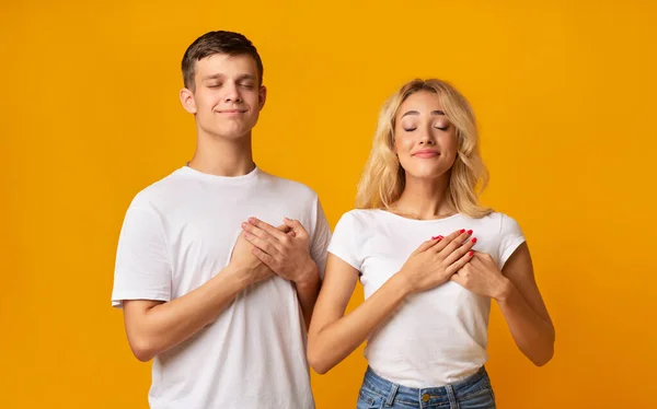 Grateful young couple keeping both palms on chest, expressing appreciation — Stock Photo, Image