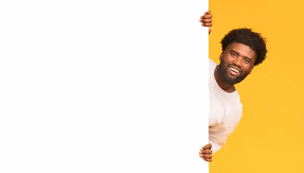 Smiling black guy looking over big blank white board — Stock Photo, Image