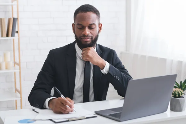 Sérieux jeune manager signant des documents dans son bureau — Photo