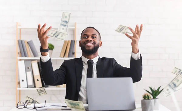 Feliz joven hombre de negocios en traje tirando dinero en el lugar de trabajo — Foto de Stock