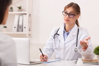Doktor Hanım hasta ile konuşuyor. Tedavi öneriyor. Ofiste oturuyor.