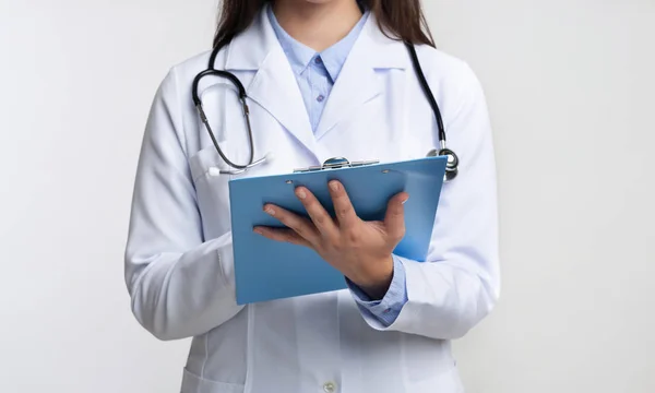 Médico irreconhecível escrevendo relatório médico em pé sobre fundo branco, cortado — Fotografia de Stock
