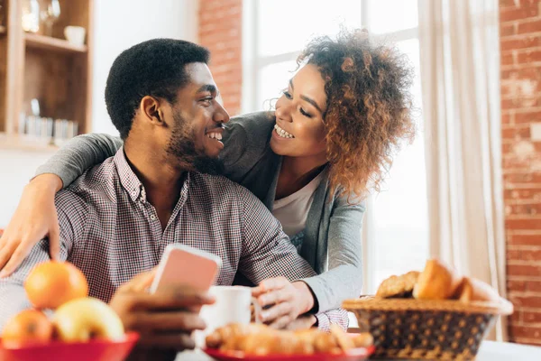 Liebendes junges Paar nutzt Smartphone in Küche — Stockfoto