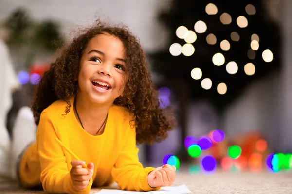 Мечтательный африканский ребенок пишет список желаний на рождественские праздники — стоковое фото