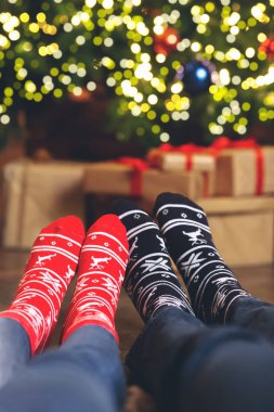 Yılbaşı çoraplarının içinde, Noel ağacının yakınındaki çiftlerin ayaklarına yakın çekim