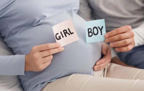 Couple holding BOY and GIRL cards in hands near pregnant belly — Stock Photo, Image