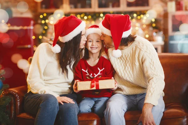 Весела маленька дівчинка з різдвяним подарунком поцілували батьки — стокове фото