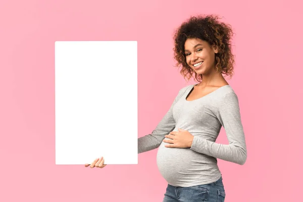 Mulher grávida sorridente com papel branco em branco — Fotografia de Stock
