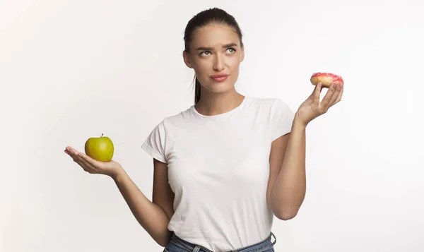 Bulmacalı Kız Donut ve Elma arasında seçim yapıyor, Beyaz Arkaplan — Stok fotoğraf