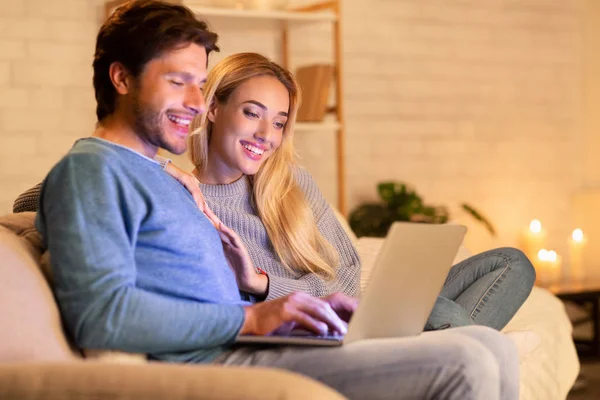 집 소파에서 편안하게 쉬고 있는 노트북에 앉아 인터넷을 하는 부부들 — 스톡 사진