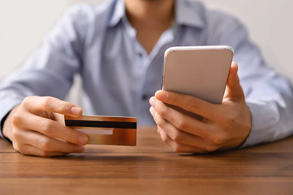 Mężczyzna trzymający smartfona i kartę kredytową, wysyłający przekaz do kogoś — Zdjęcie stockowe